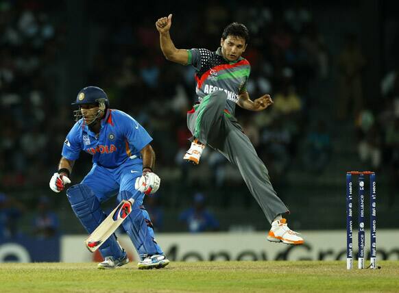 Yuvraj Singh, left, tries to run between wickets as Afghanistan's bowler Gulbodin Naib jumps during their ICC Twenty20 Cricket World Cup match in Colombo, Sri Lanka.