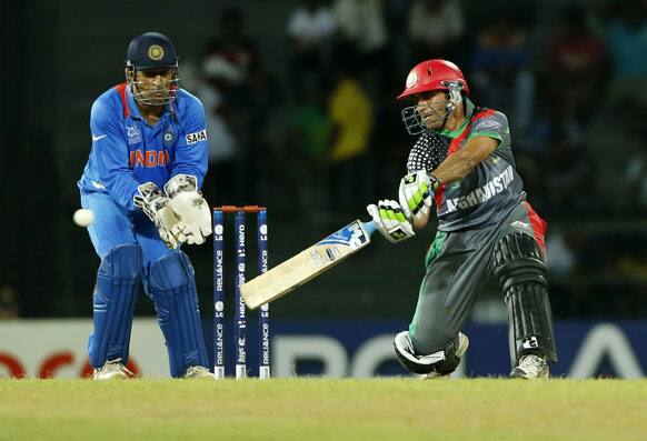 Afghanistan's batsman Karim Sadiq, right, plays a shot as India's wicket keeper Mahendra Singh Dhoni watches during their ICC Twenty20 Cricket World Cup match in Colombo.