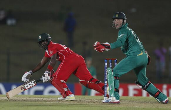 Zimbabwe's Stuart Matsikenyeri, left, bats as South Africa's captain AB de Villiers reacts during the ICC Twenty20 Cricket World Cup match between South Africa and Zimbabwe in Hambantota.