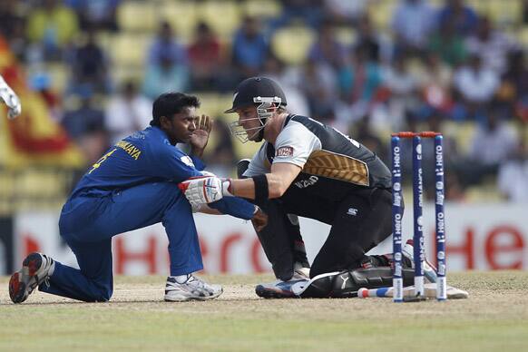 Brendon McCullum attends to Sri Lanka's bowler Akila Dananjaya after he was hurt by a shot played by McCullum's teammate Rob Nicol during the ICC Twenty20 Cricket World Cup Super Eight match in Pallekele.