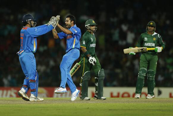 Virat Kohli, celebrates taking the wicket of Pakistan's captain Mohammad Hafeez, with Mahendra Singh Dhoni as non striker Shoaib Malik, right, looks on during the ICC Twenty20 Cricket World Cup Super Eight match between India and Pakistan in Colombo.