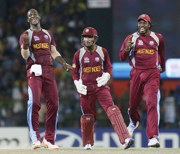 West Indies's captain Darren Sammy, left, celebrates the dismissal of Sri Lanka's batsman Angelo Mathews, unseen, with wicket keeper Denesh Ramdin, center, and Chris Gayle, right, watch during the ICC Twenty20 Cricket World Cup final match.