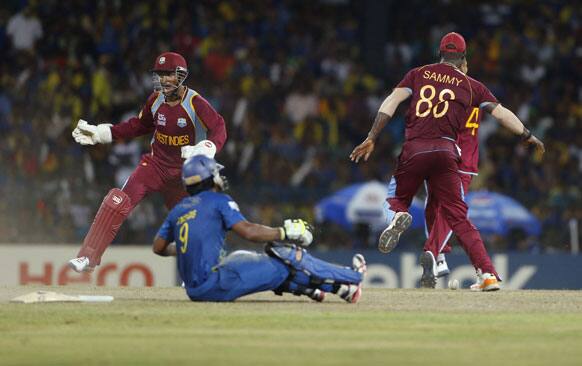 West Indies' wicketkeeper Denesh Ramdin, left, and captain Darren Sammy, right, celebrate the dismissal of Jeevan Mendis, bottom, during their ICC Twenty20 Cricket World Cup final match between Sri Lanka and West Indies' in Colombo.