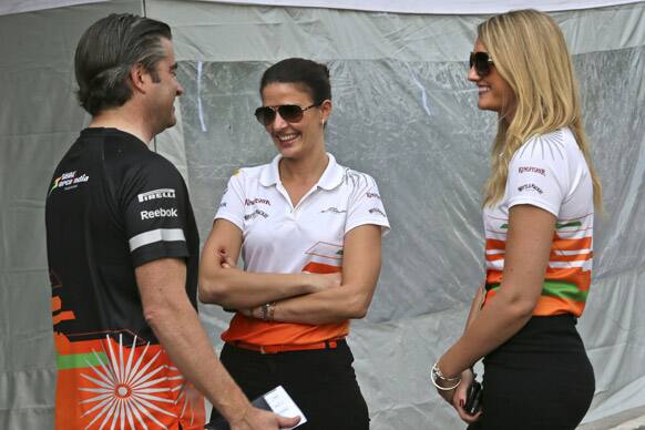 Crew members of Force India Formula One team talk outside the pit lane at the Buddh International Circuit in Noida.