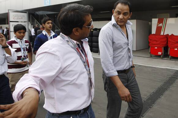 Former Indian cricket captain Mohammad Azharuddin, right, walks down the F1 paddock ahead of the Indian Formula One Grand Prix at the Buddh International Circuit in Noida.