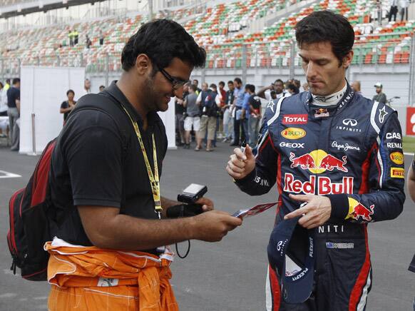 Red Bull driver Mark Webber of Australia signs his autograph for a fan ahead of the Indian Formula One Grand Prix at the Buddh International Circuit in Noida.