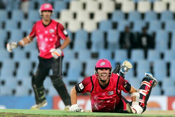 Sydney Sixers' batsman Pat Cummins, right, falls on the ground as he scores the winning run as teammate Mitchell Starc, left, looks on during the semifinal of their Champions League Twenty20 cricket match at the Centurion Stadium in Pretoria, South Africa.