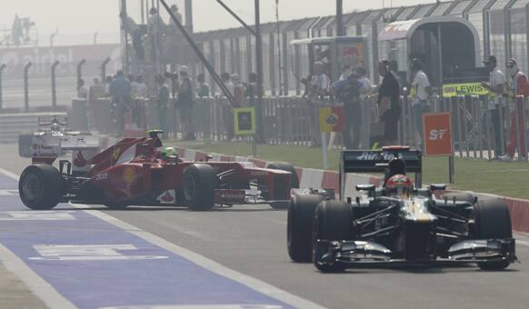 Ferrari driver Felipe Massa of Brazil steers his car out of his pit lane garage as he follows Caterham driver Heikki Kovalainen of Finland during the third practice session for the Indian Formula One Grand Prix at the Buddh International Circuit in Noida.