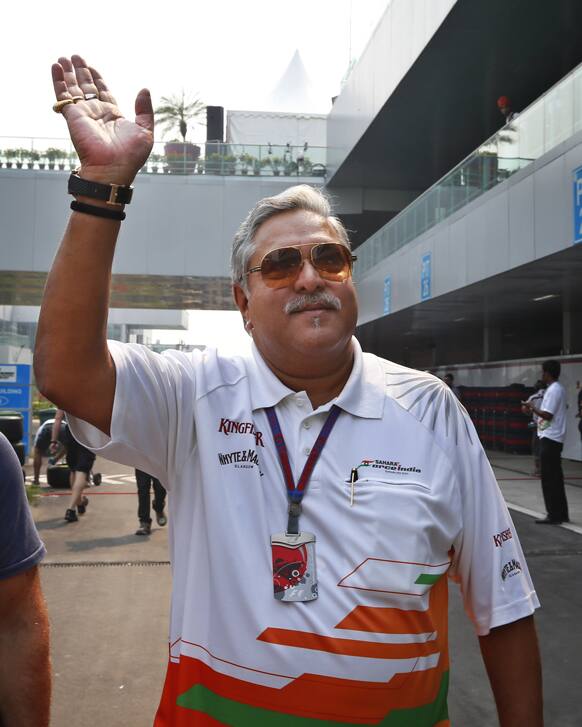 Force India team principal and businessman Vijay Mallya waves as he walks down the F1 paddock after the third practice session for the Indian Formula One Grand Prix at the Buddh International Circuit in Noida, on the outskirts of New Delhi.