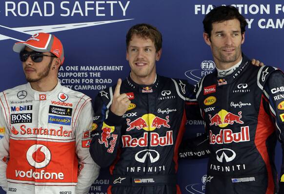 Red Bull driver Sebastian Vettel of Germany, center, poses for photos after taking pole position in the qualifying session for the Indian Formula One Grand Prix, at the Buddh International Circuit in Noida, on the outskirts of New Delhi.