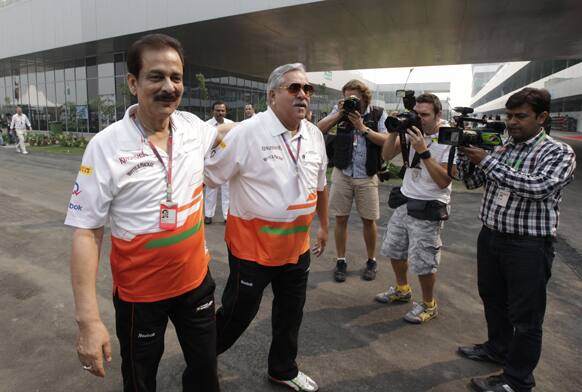 Subroto Roy, chairman of Sahara India Pariwar, left, and Force India team principal Vijay Mallya walk in the paddock before the start of the Indian Formula One Grand Prix, at the Buddh International Circuit in Noida.