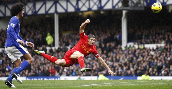 Liverpool's Steven Gerrard, center, fires a shot goalwards as Everton's Marouane Fellaini follows play during their English Premier League soccer match at Goodison Park Stadium.