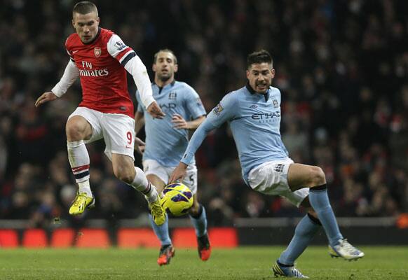 Arsenal's Lukas Podolski, left, gets past Manchester City's Javi Garcia during their English Premier League soccer match at Arsenal's Emirates Stadium in London, Sunday, Jan. 13, 2013.