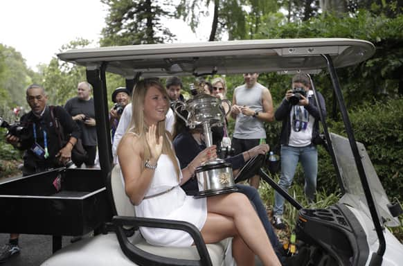 Victoria Azarenka of Belarus rides in a golf cart with the Australian Open trophy after posing with it for photographers in the Royal Botanical Gardens following her win over China's Li Na in the women's final, in Melbourne.