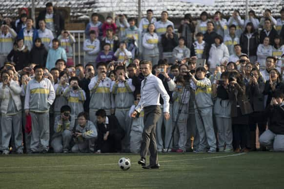 David Beckham, in his suit, plays soccer with students of Beijing's No. 2 High School during an event to promote the sport in China.