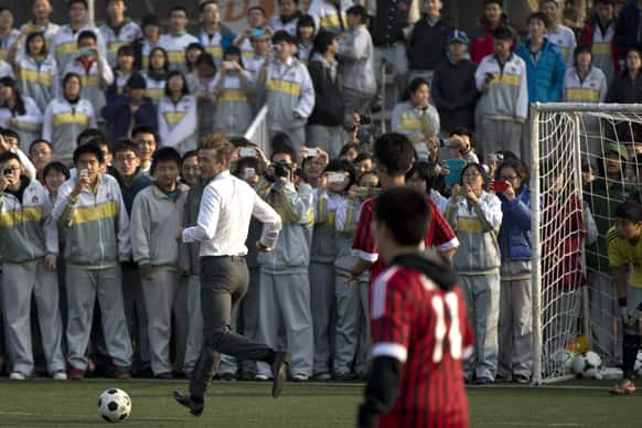 David Beckham, in his suit, plays soccer with students of Beijing's No. 2 High School during an event to promote the sport in China.