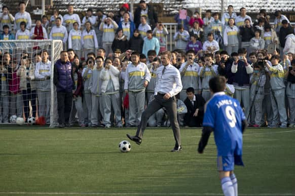 David Beckham of Britain, in his suit, plays soccer with students of Beijing's No. 2 High School during an event to promote the sport in China.