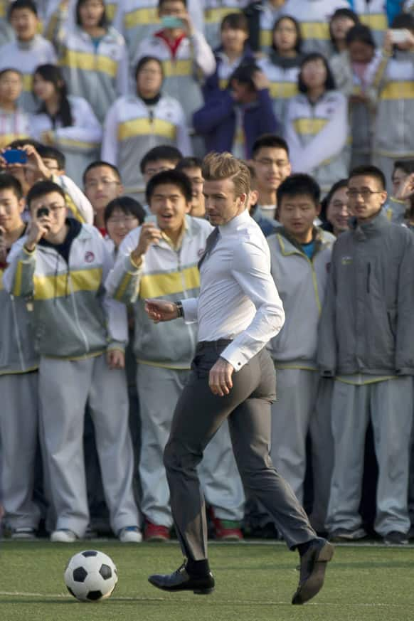 David Beckham, in his suit, plays soccer with students of Beijing's No. 2 High School during an event to promote the sport in China.