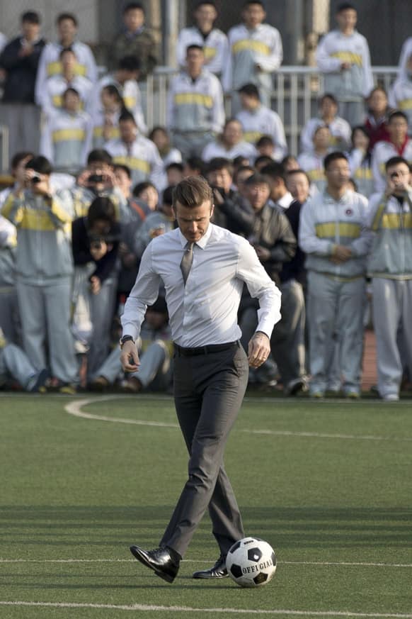 David Beckham, in his suit, plays soccer with students of Beijing's No. 2 High School during an event to promote the sport in China.