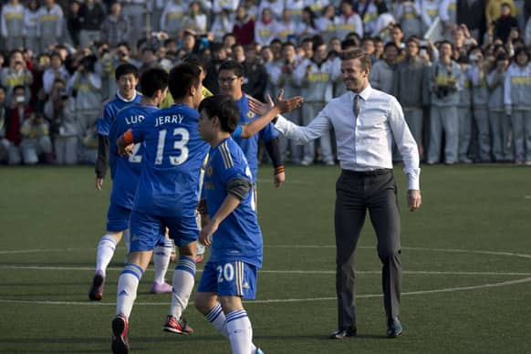 David Beckham, celebrates with a teammate after a goal while he plays soccer with students of Beijing's No. 2 High School during an event to promote the sport in China.