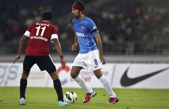 Bollywood actor Ranbir Kapoor, right, dribbles a ball during a charity soccer match played between Indian cricket players and Bollywood actors in New Delhi.