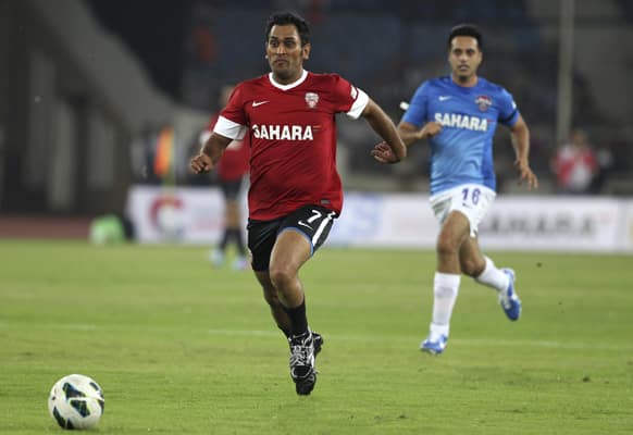 Mahendra Singh Dhoni, center, runs after a ball during a charity soccer match played between Indian cricket players and Bollywood actors in New Delhi.