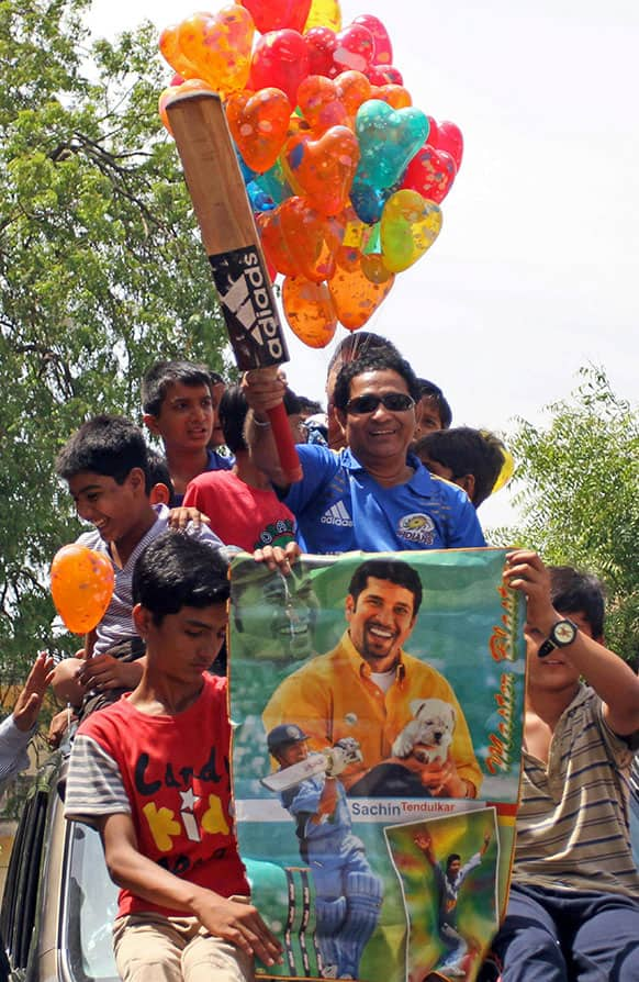 Suresh Rathod, a look-alike of Indian cricketer Sachin Tendulkar, holds a bat during celebrations marking Tendulkar’s birthday in Ahmadabad.