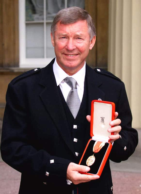 In this Tuesday, July 20, 1999 file photo Manchester United soccer manager Sir Alex Ferguson holds his knighthood insignia that was presented to him by Britain's Queen Elizabeth during an Investiture ceremony at Buckingham Palace, London.