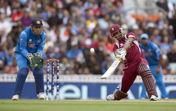 West Indies' Johnson Charles hits a shot beside India's captain and wicketkeeper Mahendra Singh Dhoni during the ICC Champions Trophy group B cricket match between India and West Indies at The Oval cricket ground in London.