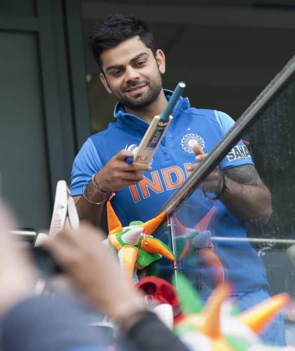 Virat Kohli signs autographs as rain falls at Edgbaston cricket ground before his team's ICC Champions Trophy Final cricket match against England.