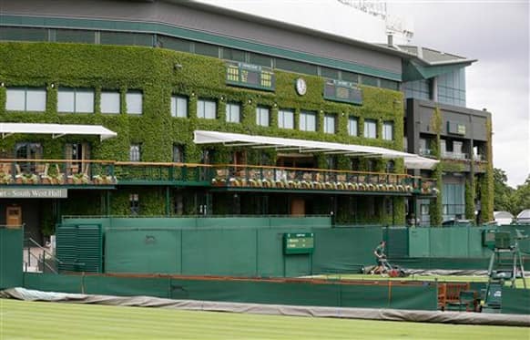 Groundsmen make final preparations on the outside courts backdropped by Centre Court, for the start of the Wimbledon tennis championships in London.