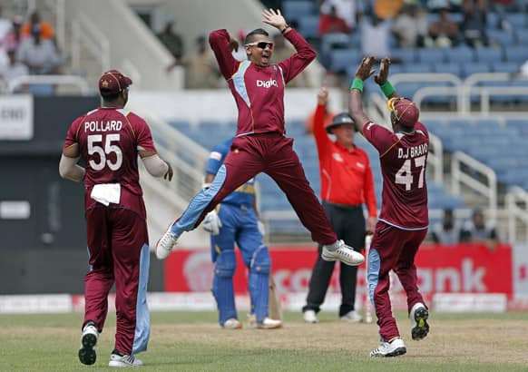 Sunil Narine, jumps to high five with his captain Dwayne Bravo, as teammate Kieron Pollard watches, after taking the wicket of Sri Lanka's opening batsman Mahela Jayawardene for 52 runs during their Tri-Nation Series cricket match in Kingston, Jamaica.