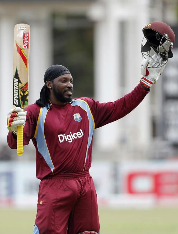 West Indies opening batsman Chris Gayle raises his bat and helmet after scoring a century during the Tri-Nation Series cricket match against Sri Lanka in Kingston, Jamaica.