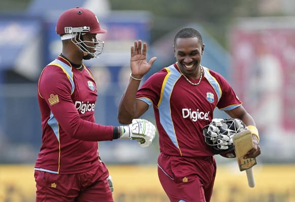 West Indies' captain Dwayne Bravo, right, celebrates with batting partner Marlon Samuels after beating Sri Lanka by 6 wickets with 73 balls remaining during their Tri-Nation Series cricket match in Kingston, Jamaica.