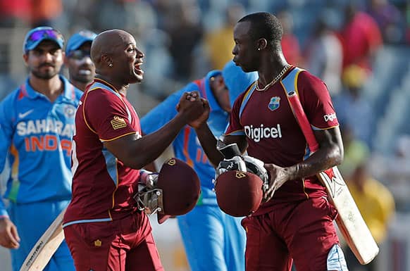 West Indies' Tino Best, left, and his batting partner Kemar Roach shake hands after they team beat India by one wicket in their Tri-Nation Series cricket match in Kingston, Jamaica.