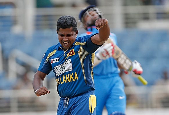 Sri Lanka bowler Rangana Herath celebrates after taking the wicket of India opening batsman Shikhar Dhawan, who reacts in the background, during their Tri-Nation Series cricket match in Kingston, Jamaica.