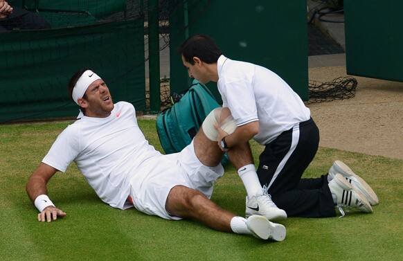 Juan Martin Del Potro of Argentina receives treatment after falling during his Men's singles quarterfinal match against David Ferrer of Spain at the All England Lawn Tennis Championships in Wimbledon, London.