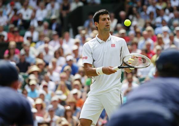 Ballboys watch as Novak Djokovic of Serbia gathers balls as he plays Juan Martin Del Potro of Argentina during their Men's singles semifinal match at the All England Lawn Tennis Championships in Wimbledon.