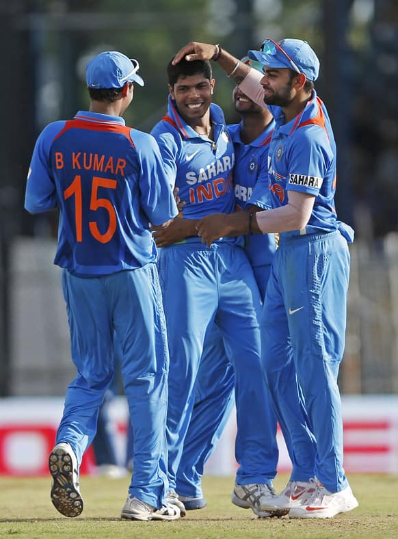 Umesh Yadav, center, is congratulated by teammates after taking the wicket of West Indies' Denesh Ramdin, who was caught by Bhuvneshwar Kumar for nine runs, during their Tri-Nation Series cricket match in Port-of-Spain.