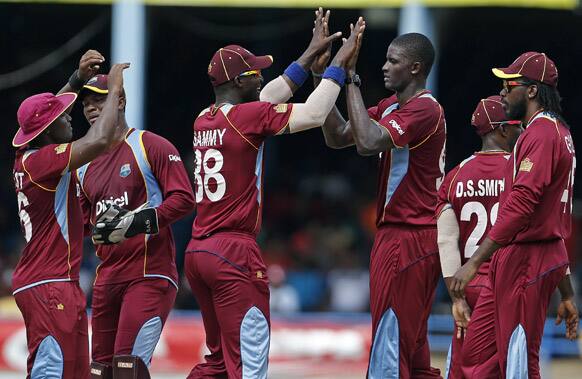 West Indies bowler Jason Holder, third from right, is congratulated by teammates after taking the wicket of Sri Lanka opening batsman Upul Tharanga, who was caught by Darren Bravo for 7 runs, during their Tri-Nation Series cricket match in Port-of-Spain.