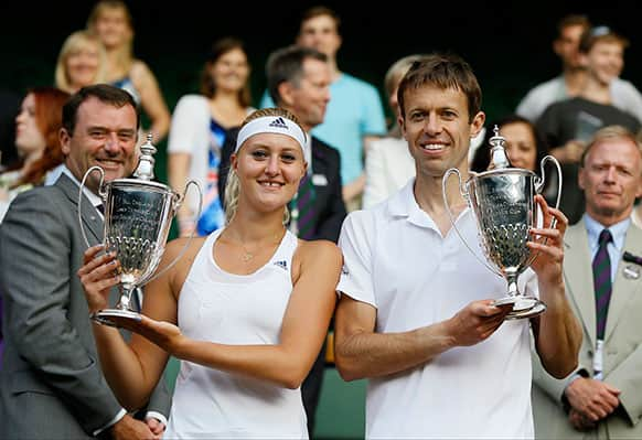 Daniel Nestor of Canada, right, and Kristina Mladenovic of France pose with their trophies after they won against Bruno Soares of Brazil and Lisa Raymond of the United States in the mixed doubles final match at the All England Lawn Tennis Championships in Wimbledon.