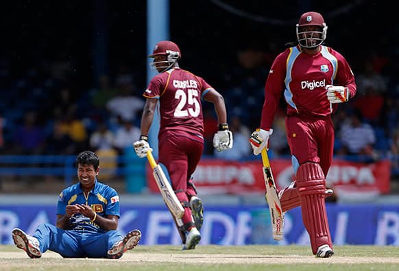 Sri Lanka bowler Nuwan Kulasekara, left, grimaces after injuring a finger trying to intercept a shot off West Indies' Chris Gayle, right, who runs between the wickets with batting partner Johnson Charles during their Tri-Nation Series cricket match in Port-of-Spain, Trinidad.