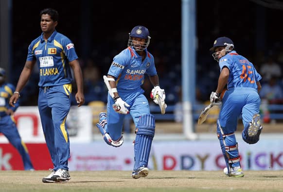 India opening batsmen Shikhar Dhawan, center, and Rohit Sharma, right, run between the wickets as Sri Lanka bowler Dilhara Lokuhettige looks on during their Tri-Nation Series cricket match in Port-of-Spain.