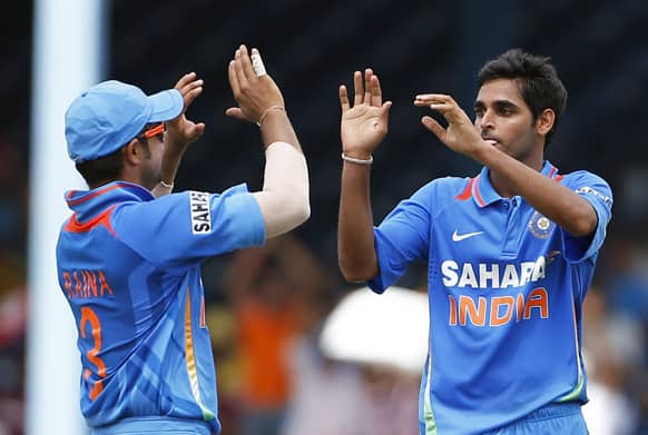 India bowler Bhuvneshwar Kumar, right, high fives with teammate Suresh Raina after taking the wicket of Sri Lanka opening batsman Mahela Jayawardene, who was caught by Ravichandran Ashwin for 22 runs, during the final match of the Tri-Nation cricket series in Port-of-Spain, Trinidad.