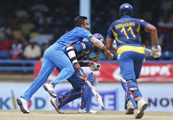 Suresh Raina gets tangled with non-striking batsman Lahiru Thirimanne after missing a chance to catch a shot of Sri Lanka's Kumar Sangakkara off his own bowling during the final match of the Tri-Nation cricket series in Port-of-Spain, Trinidad.