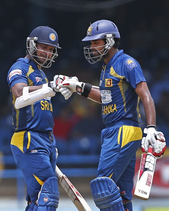 Sri Lanka's Kumar Sangakkara, left, knocks the glove with batting partner Lahiru Thirimanne to congratulate him for hitting a four during the final match against India of the Tri-Nation cricket series in Port-of-Spain.