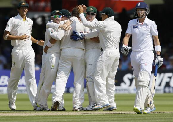 England's Joe Root leaves the pitch past Australian celebrations after being out LBW off the bowling of Australia's Ryan Harris during the Ashes test at Lord's cricket ground in London.