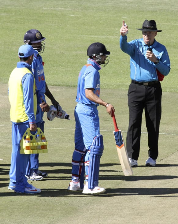 Virat Kohli, second from right, is given a signal to get out after he was caught for 14 runs on the second day of the one day international cricket match against Zimbabwe, in Harare.