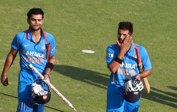 Virati Kohli, left and Suresh Raina walk off the pitch after beating Zimbabwe by 7 wickets during their third one-day international cricket match, in Harare.