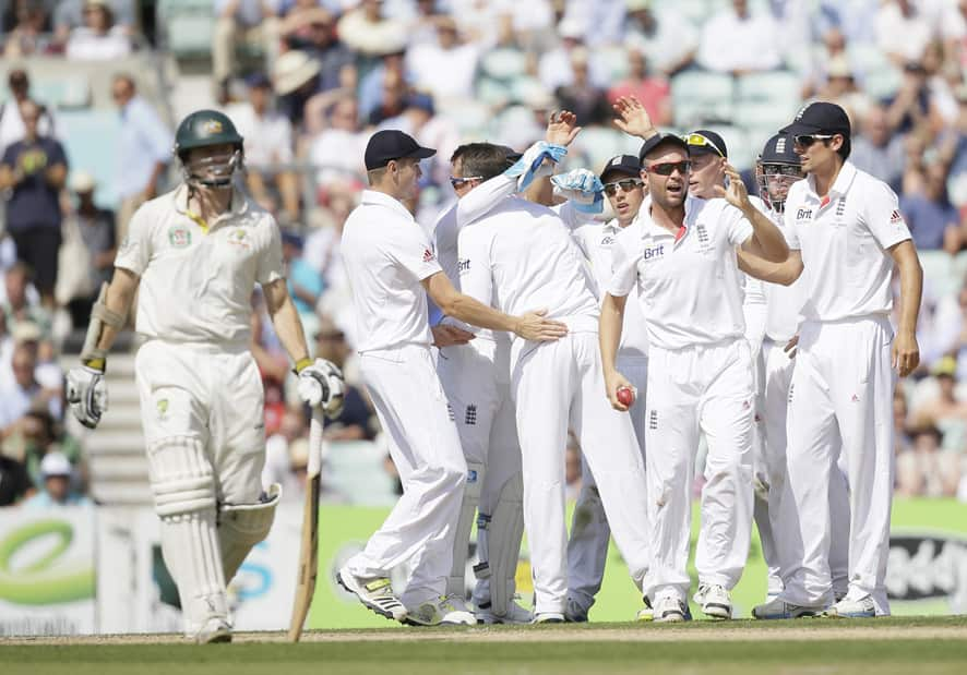 England's Jonathan Trott, second right, celebrates with teammates after catching out Australia's Chris Rogers who is walking off the pitch, left, during play on the first day of the fifth Ashes cricket Test at the Oval cricket ground in London.